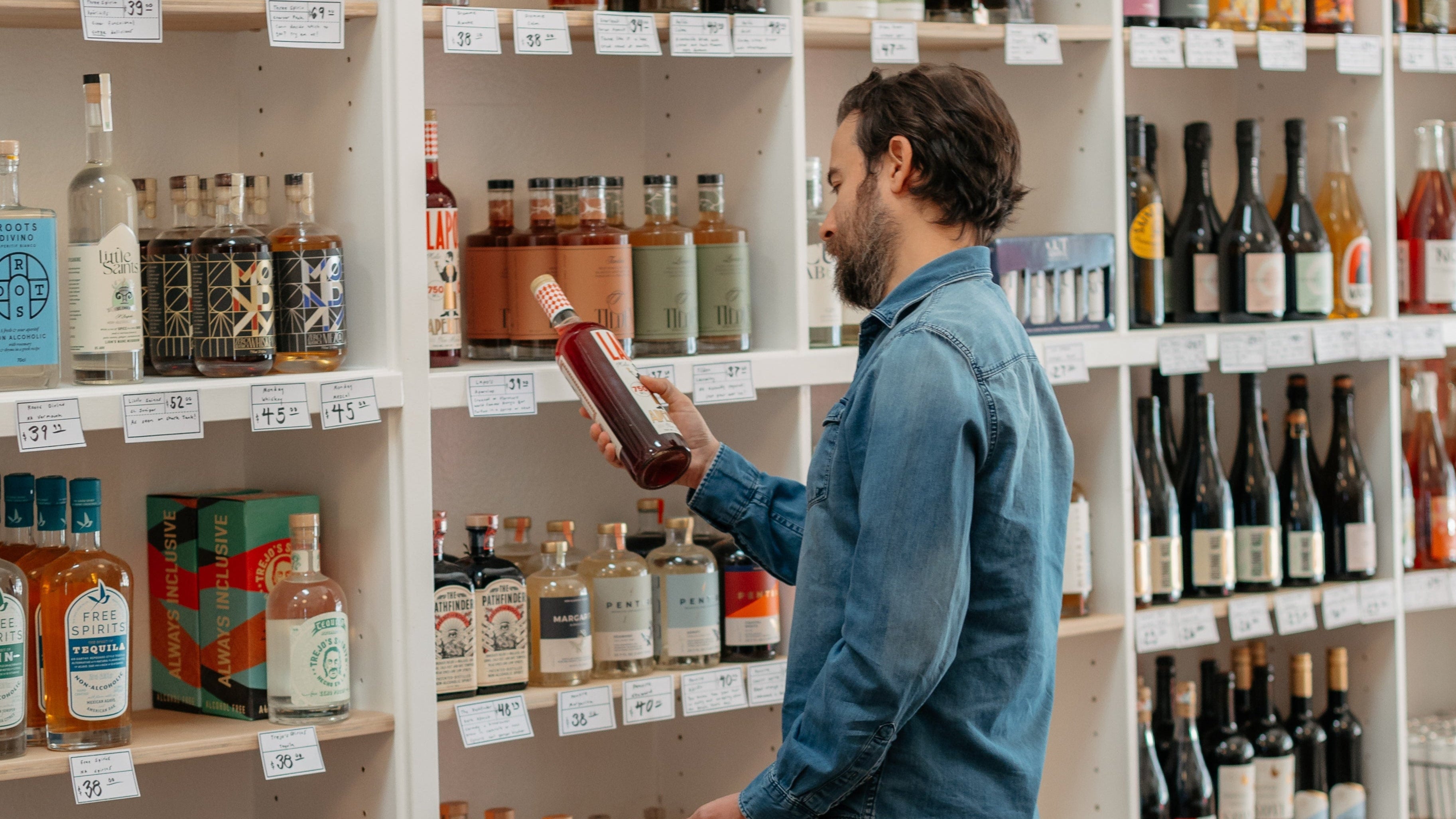 Man shopping in a non-alcoholic store with shelves stocked with various bottles.