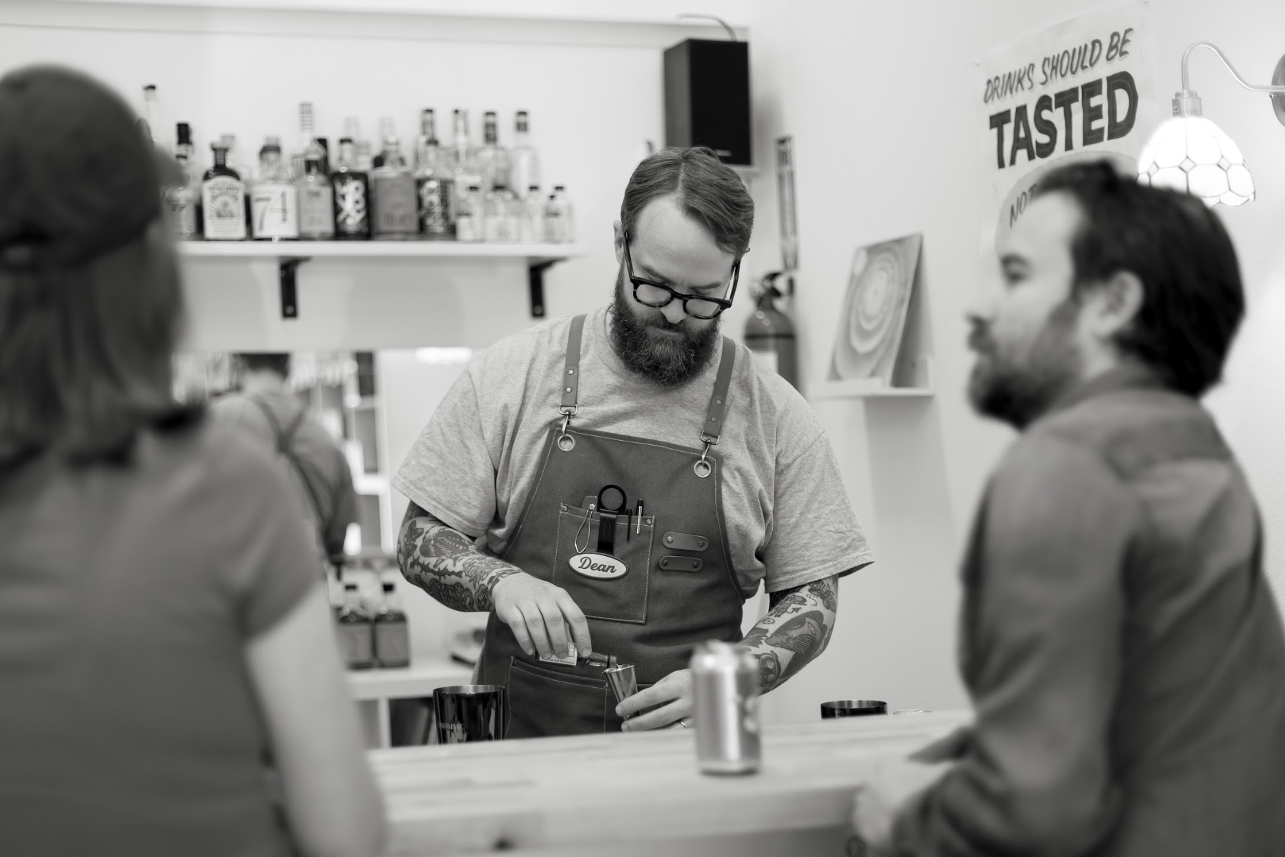 bartender serving a customer in a bar with a mirror reflecting the bartender.